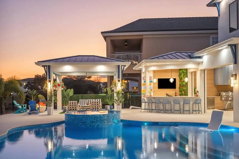 Luxurious backyard pool area with a built-in hot tub, outdoor kitchen, and modern seating at sunset St. Augustine St. Johns County FL