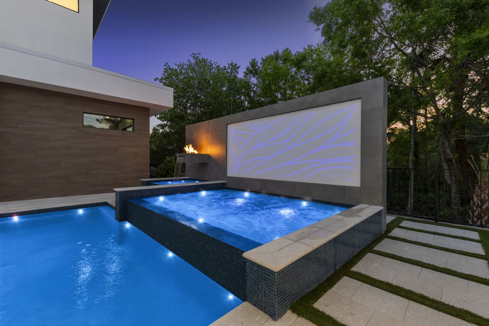 Modern backyard pool with water features and ambient lighting in West Kissimmee