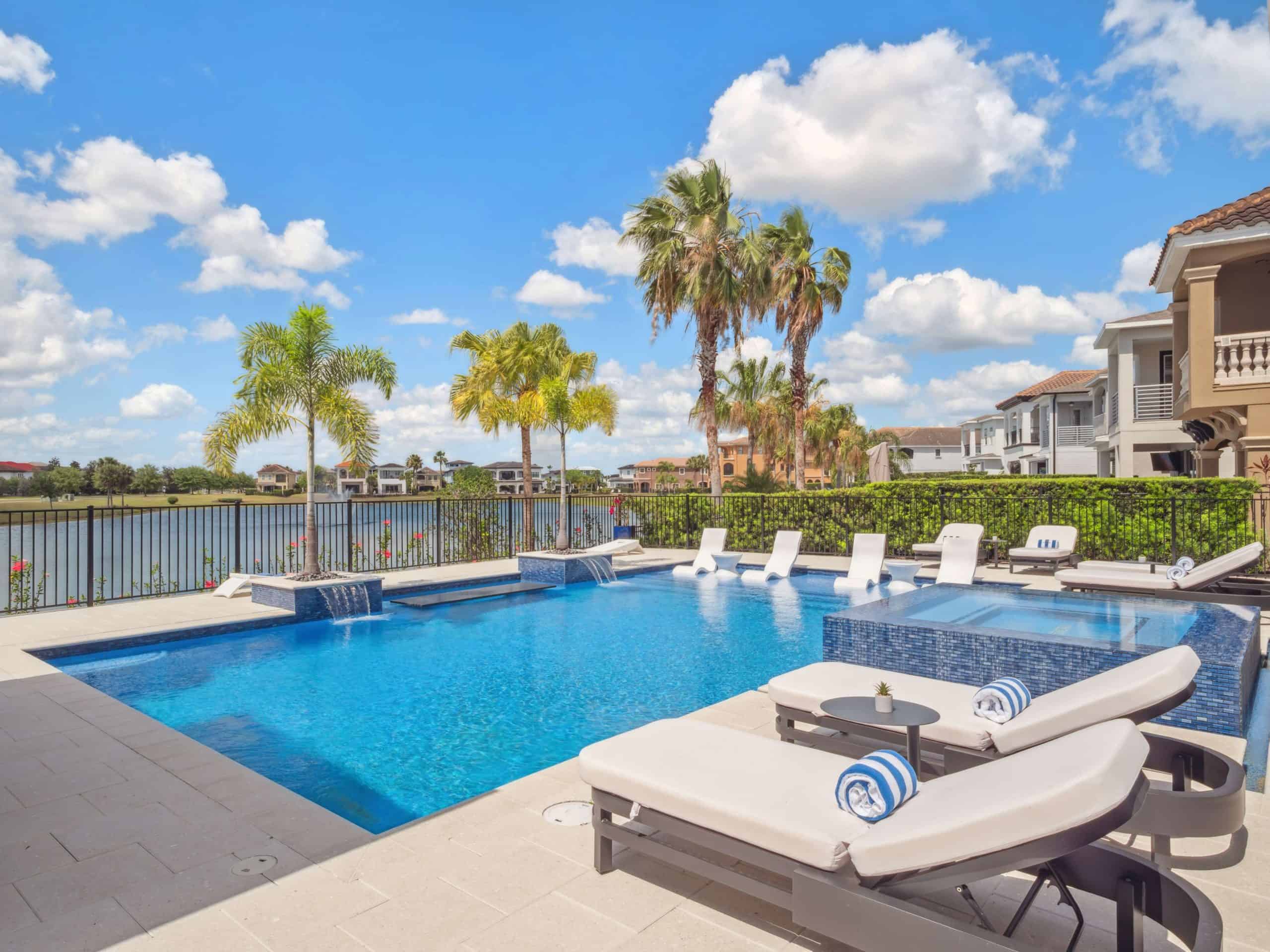 Upscale backyard pool with waterfall features, palm trees, and waterfront homes in New Smyrna Beach, Volusia County FL