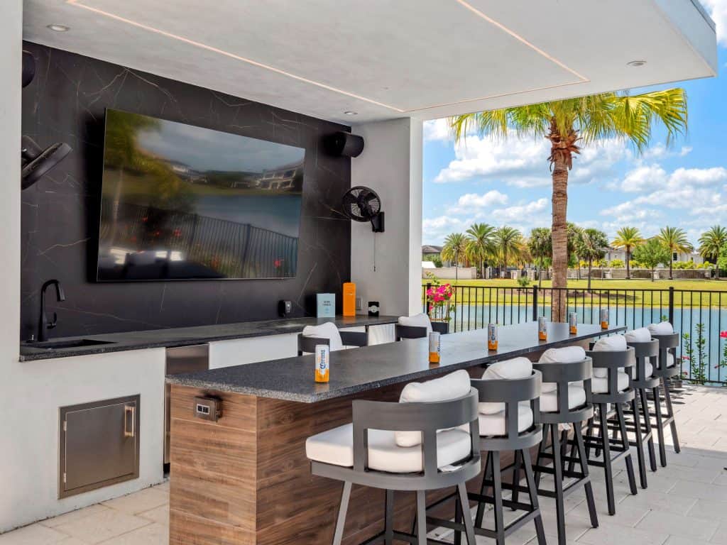 High-end outdoor kitchen and poolside bar with seating and a lake view in Florida
