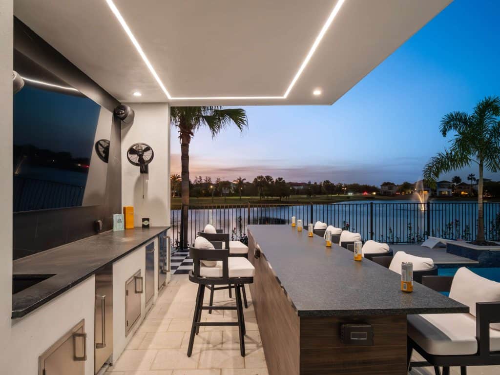 Modern outdoor kitchen and poolside bar overlooking a lake at sunset in Central Florida