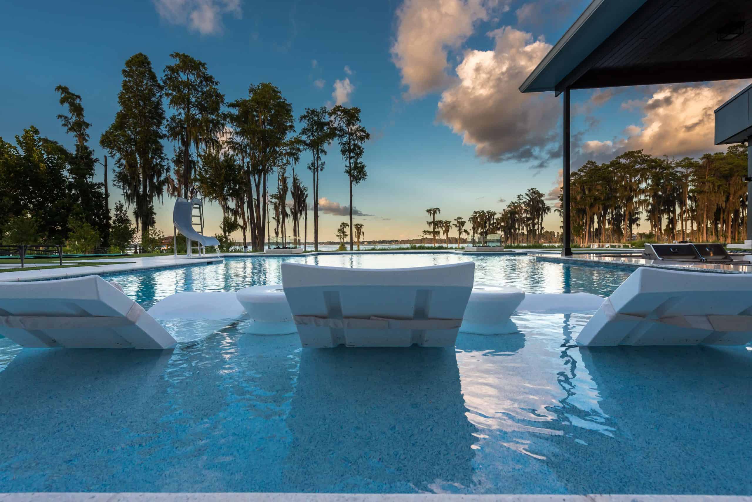 Contemporary backyard pool with white lounge chairs and a waterslide in Timacuan, Lake Mary FL
