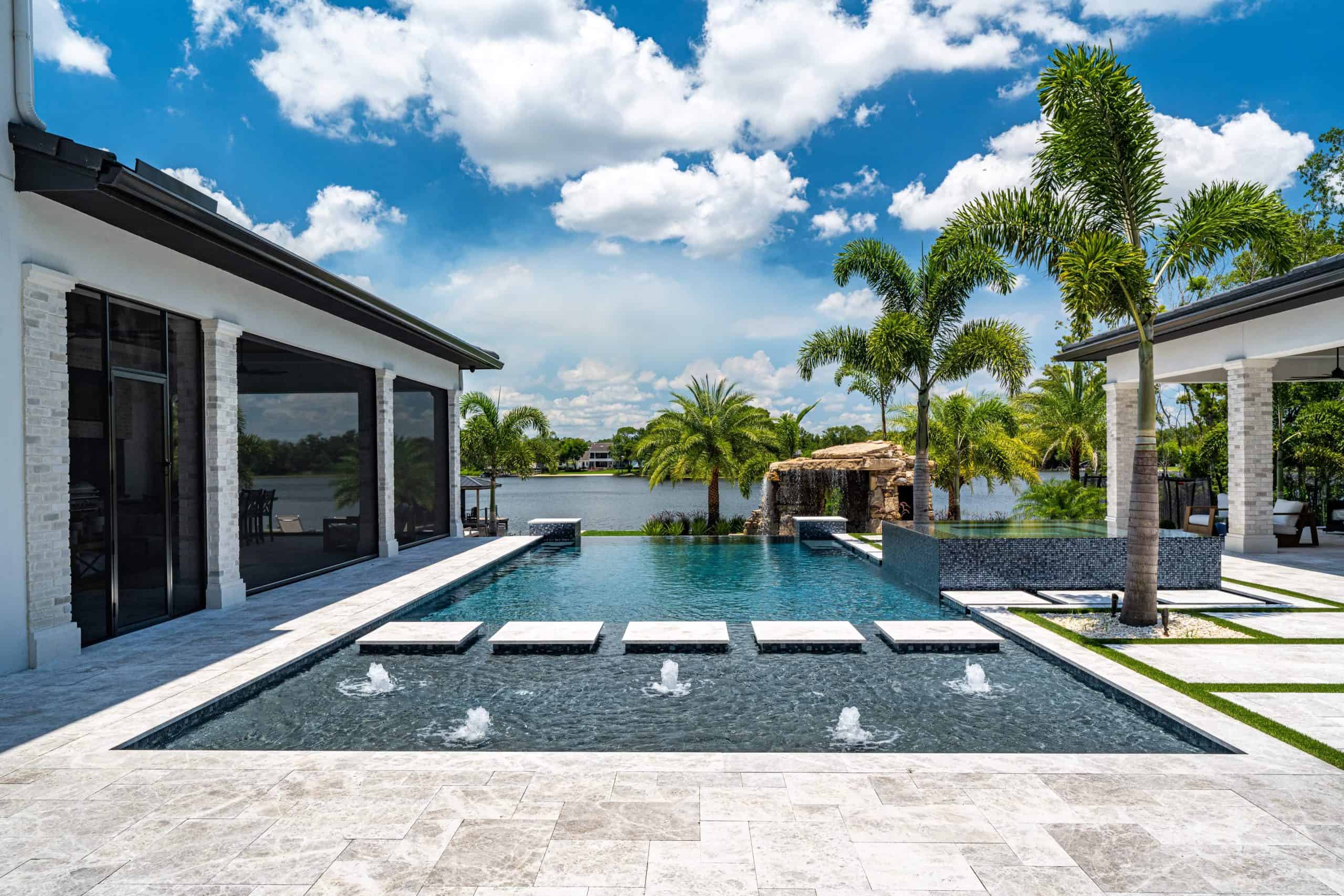 Modern backyard pool with waterfall feature, palm trees, and outdoor seating in Daytona Beach, Volusia County FL