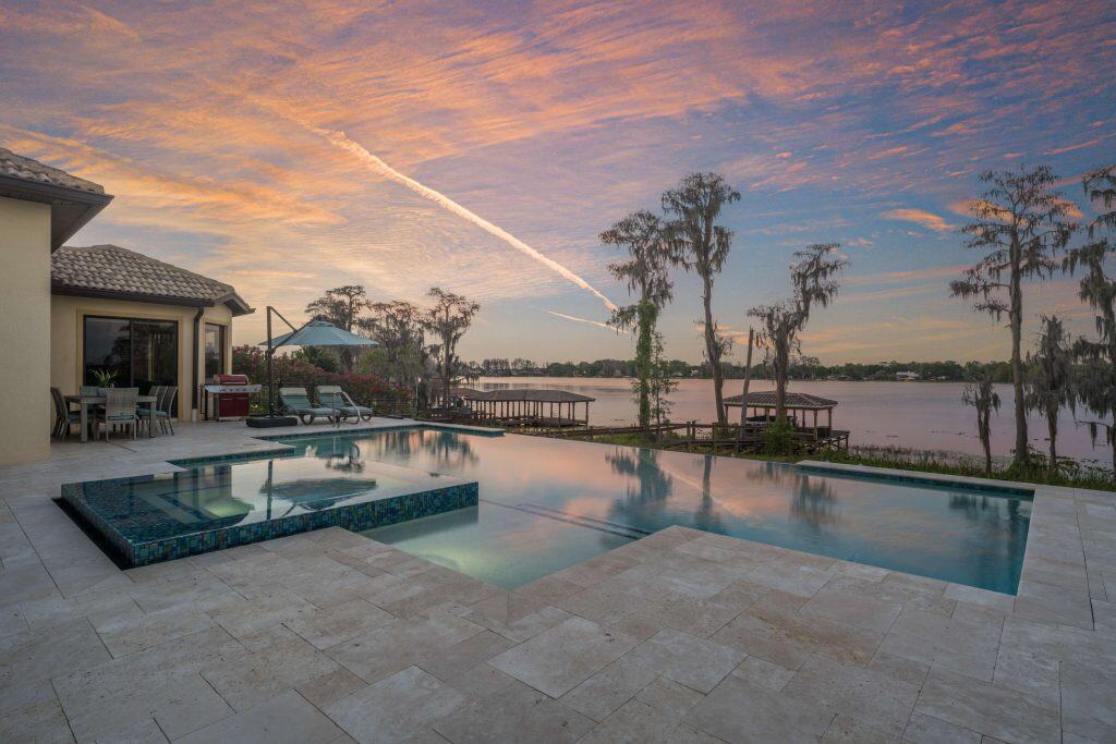 Luxury infinity pool with a sunset view over the water and outdoor living space in Florida