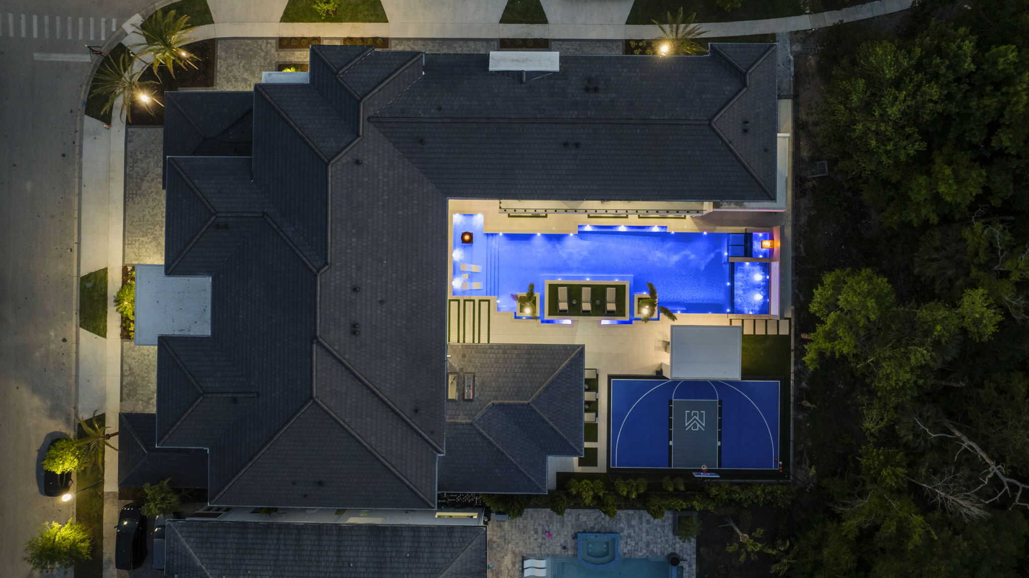 Illuminated backyard pool with modern outdoor furniture at night in Longwood, Seminole County FL