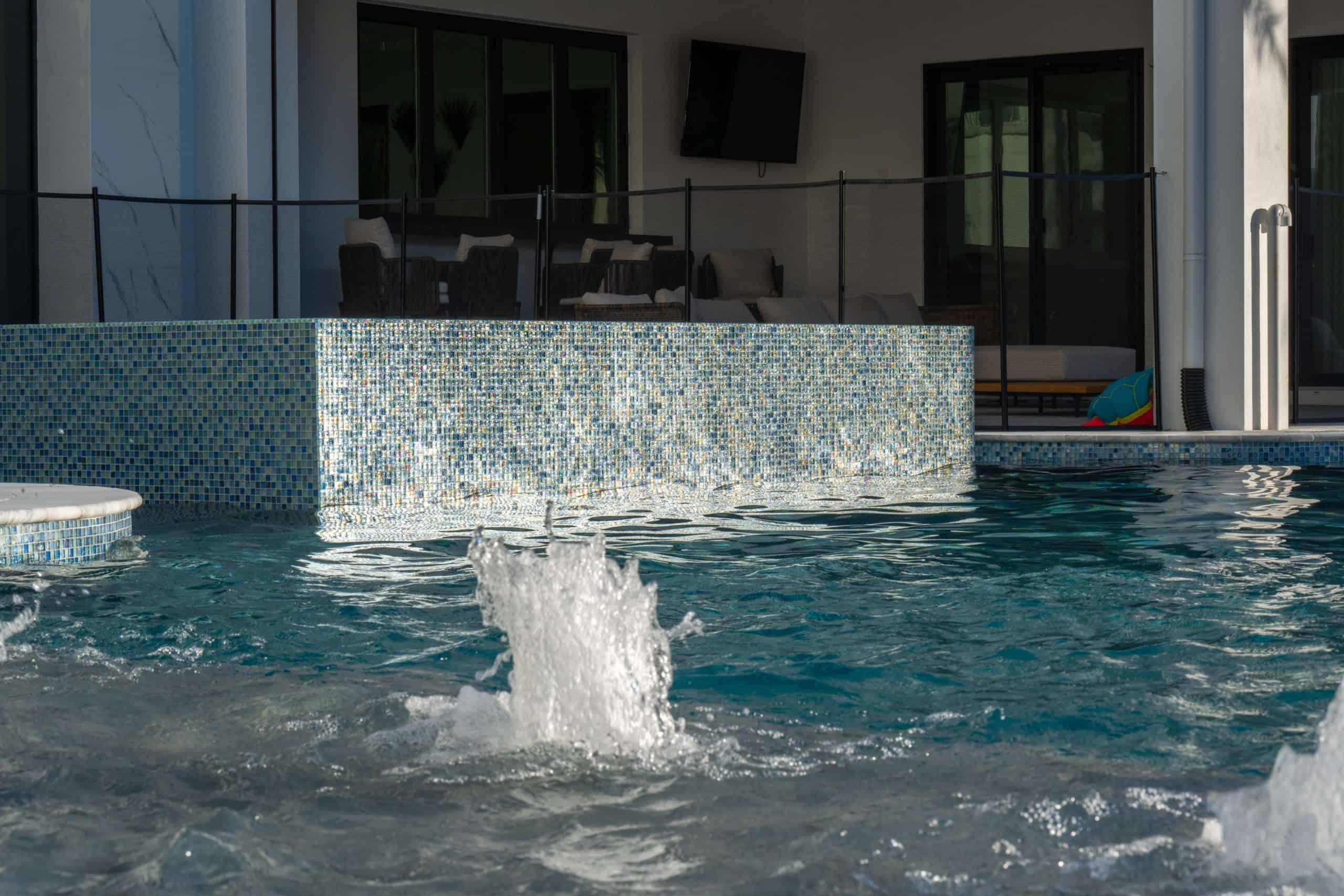 TungPhotography12 Luxurious backyard pool with modern water features and elegant mosaic tile design.