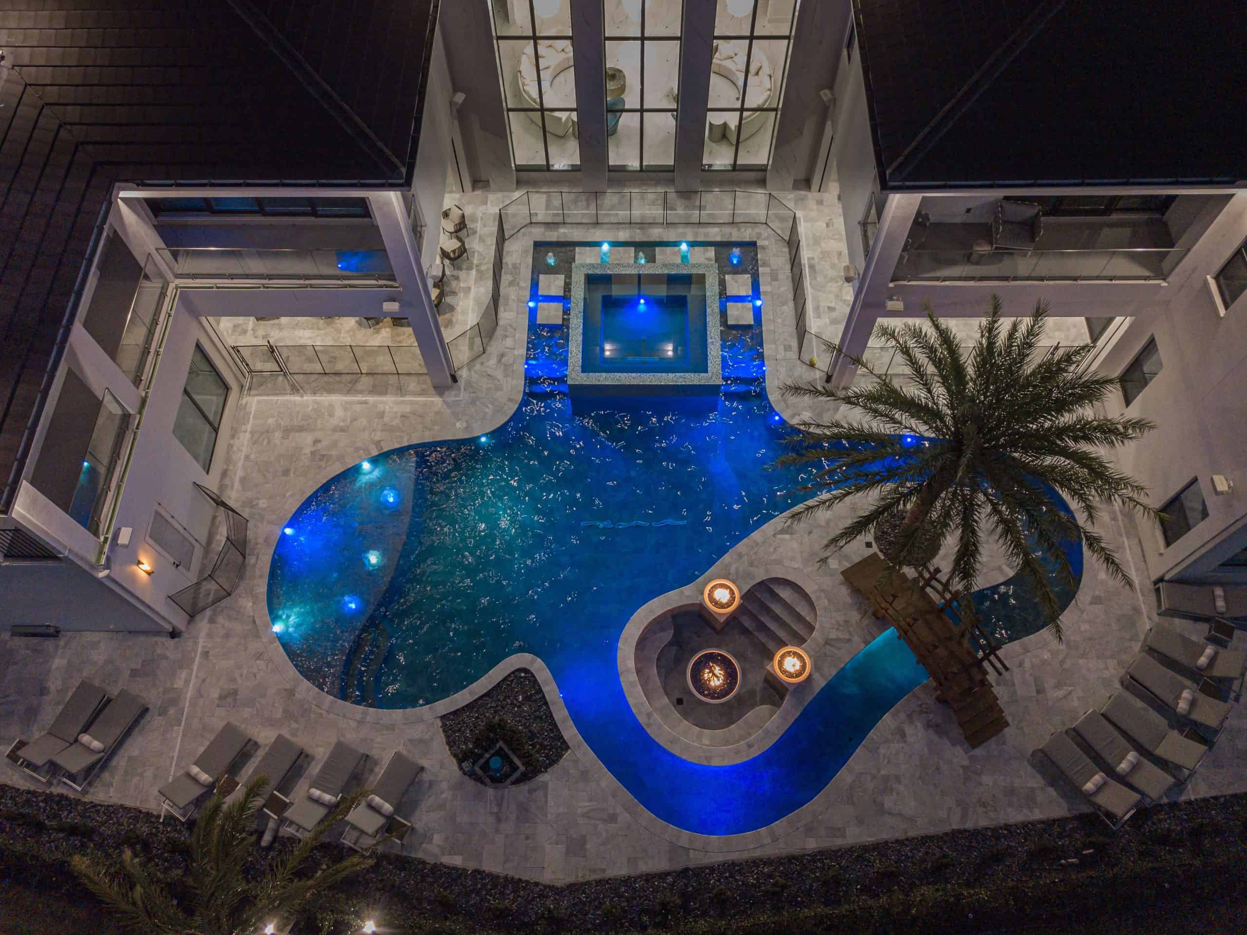 Luxurious backyard pool with modern design illuminated at night, featuring a hot tub and cozy fire pit in Historic District & Downtown Homes