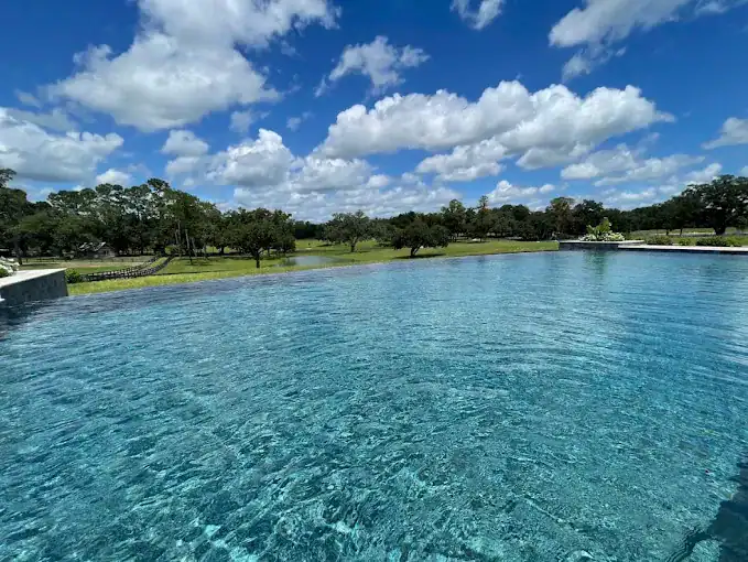Stunning custom-designed high-end pool surrounded by lush green landscape and vibrant blue sky in Lake Lona Orange County FL