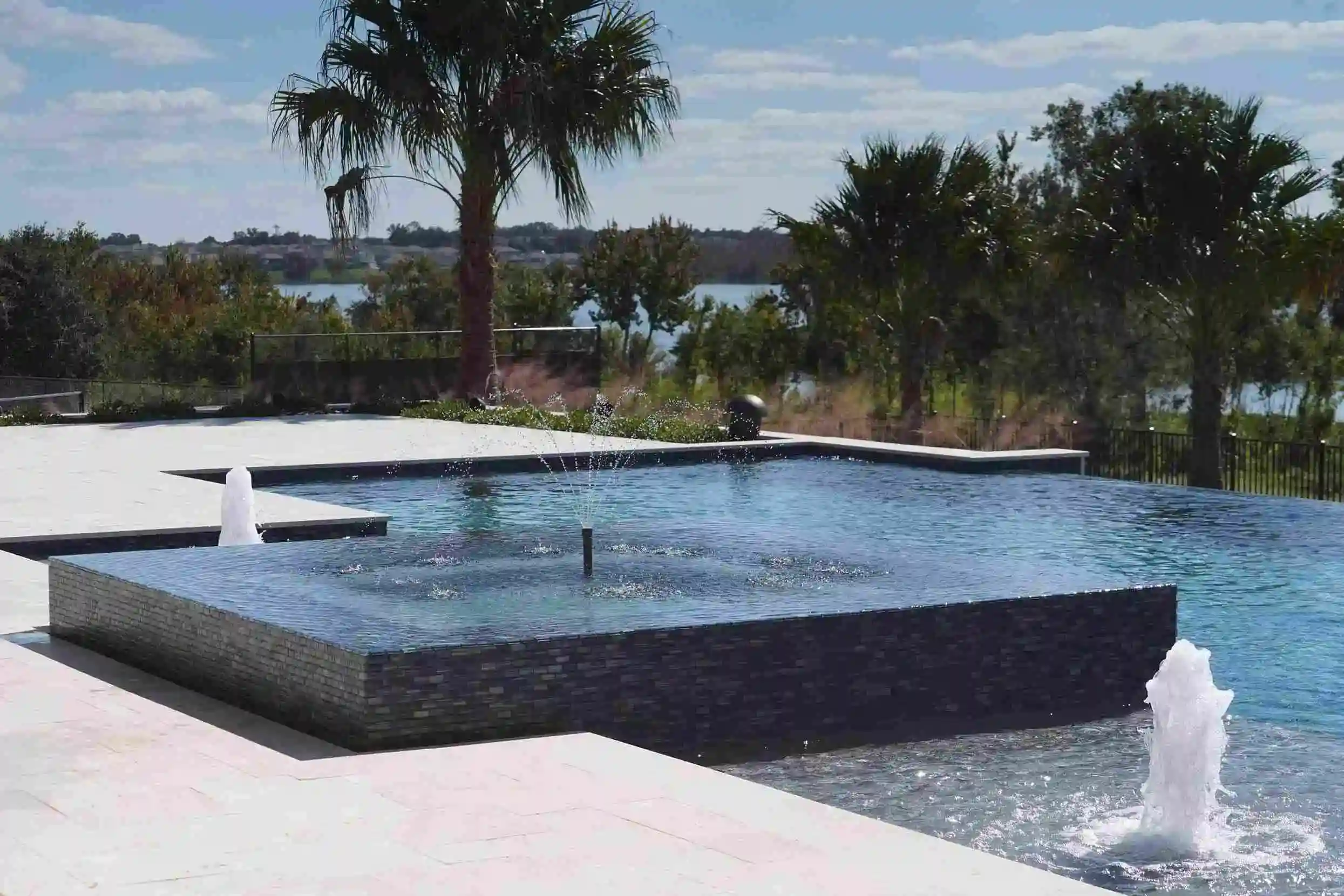 Luxury modern outdoor pool with waterfalls and surrounding palm trees, scenic waterfront view, perfect for relaxation and entertaining in Orange County FL