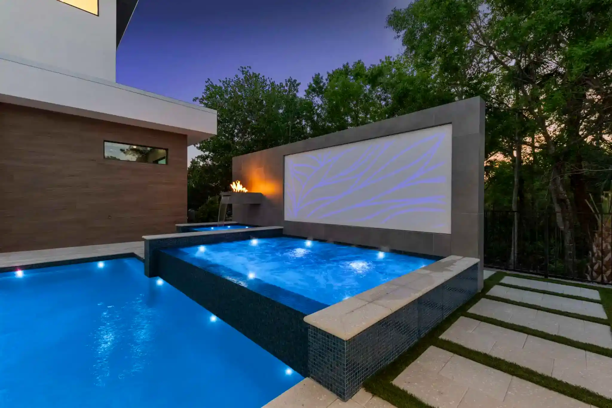 Modern backyard pool with water features and ambient lighting in West Kissimmee