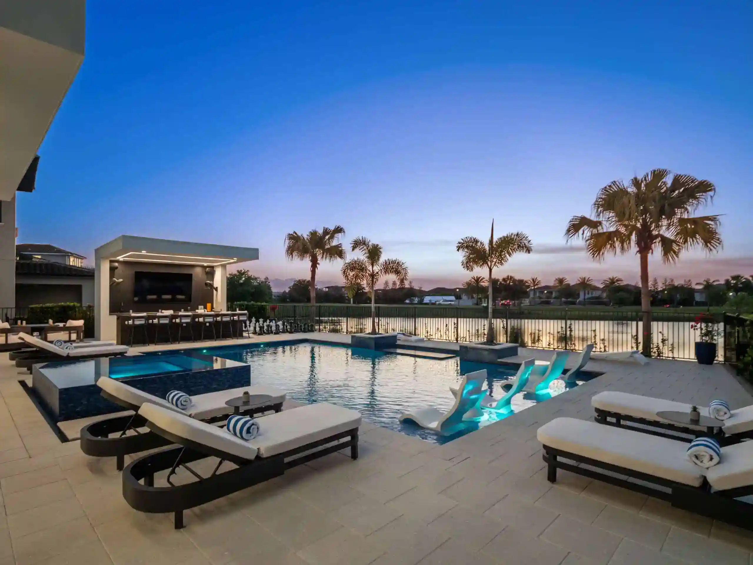 Luxurious modern outdoor pool with sundeck and palm trees at sunset in Lake Mary, Seminole County FL