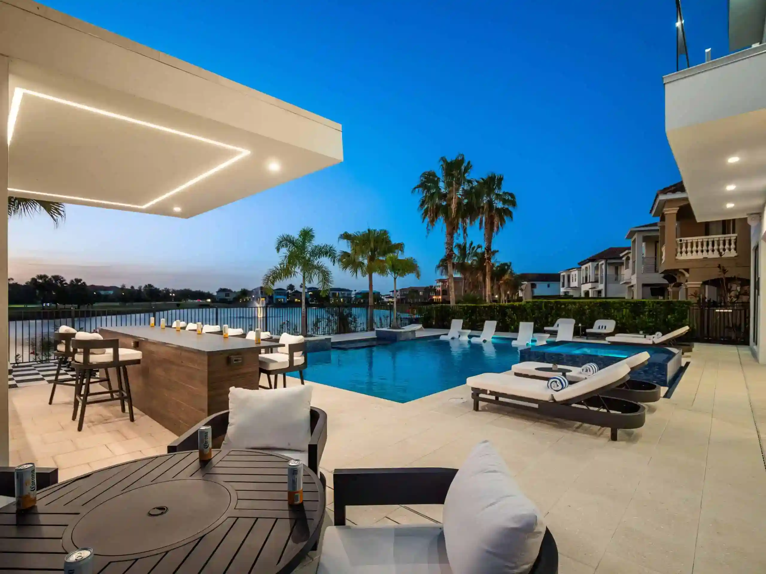 Modern backyard pool with lounge chairs and palm trees at sunset in Restaurant Row Estates, Dr. Phillips FL