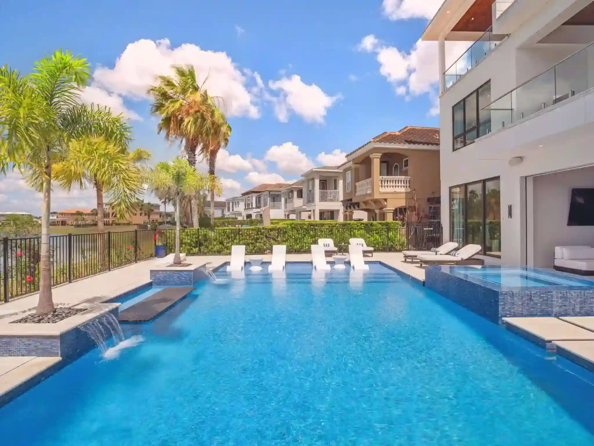 Backyard pool with waterfalls, lounge chairs, and modern outdoor living space in South Village, Celebration