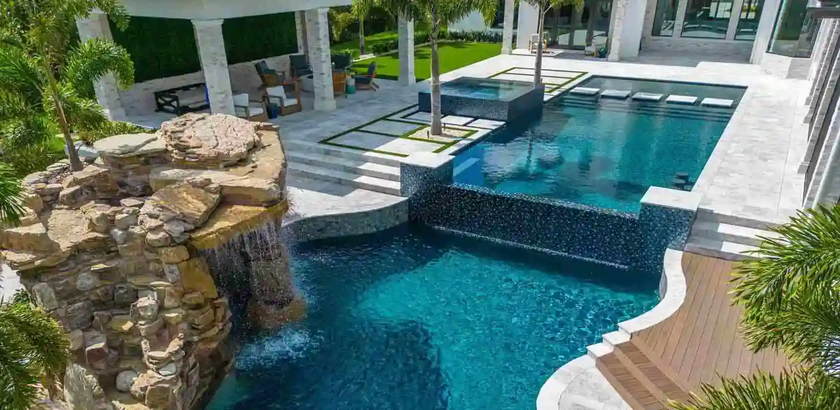High-end backyard pool featuring waterfall, spa, and modern design elements.