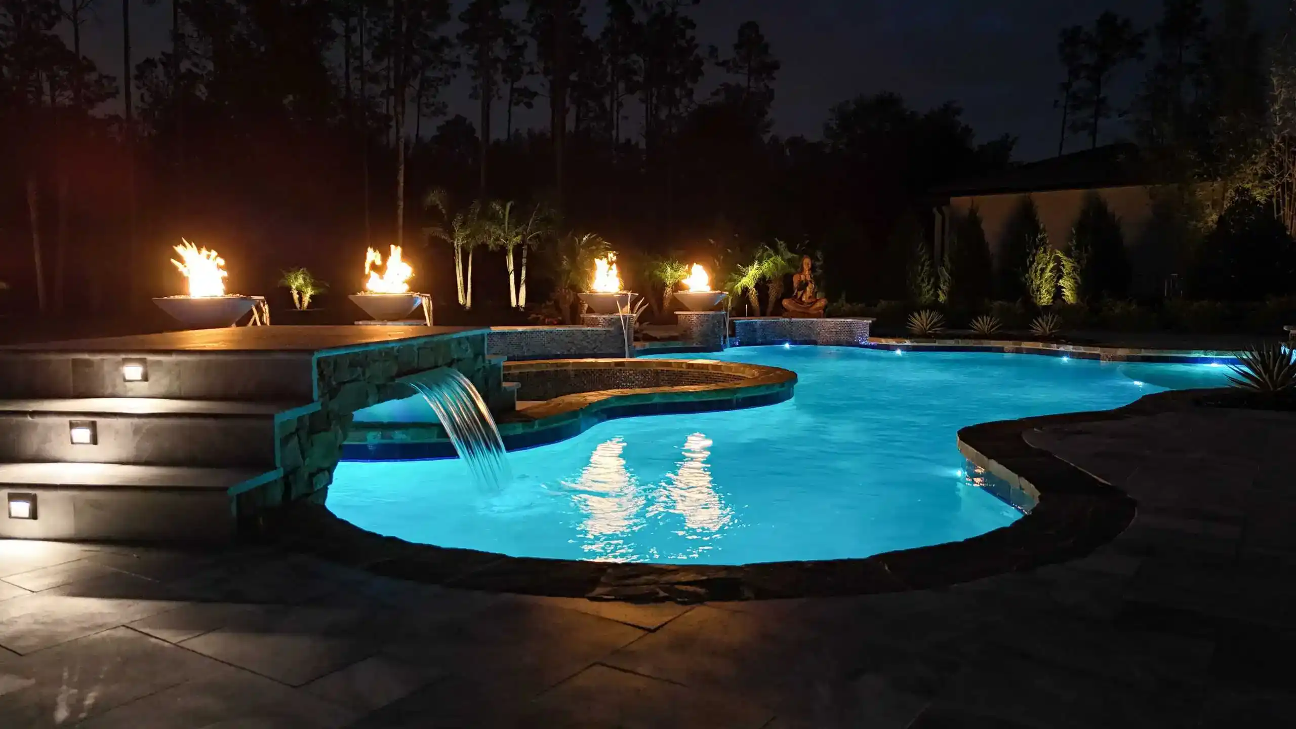 High-end residential swimming pool with sleek design, tanning ledge, and tropical landscaping.