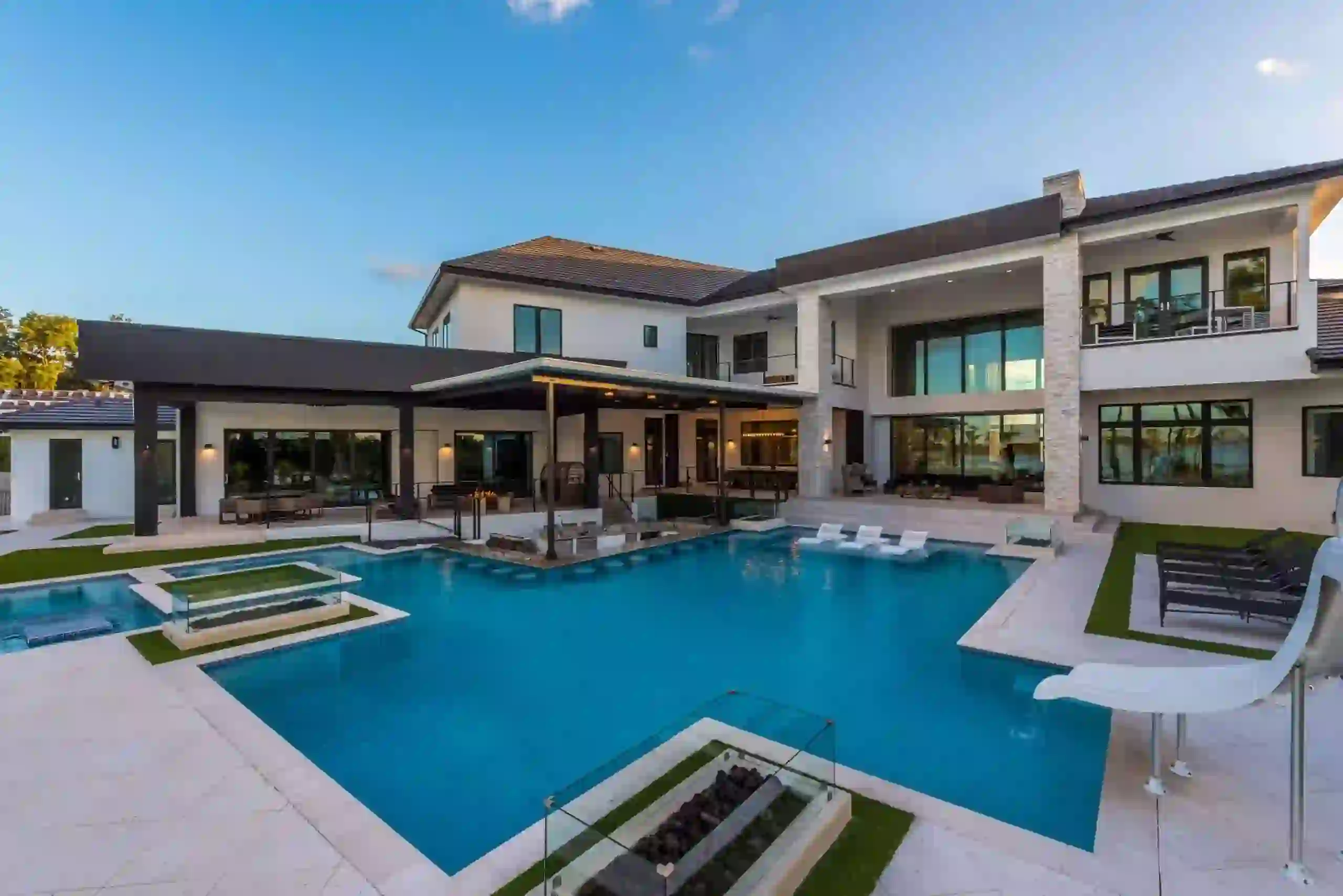 Luxury custom backyard pool with modern design and outdoor living space. Stunning modern luxury outdoor pool with stylish lounge areas and fire features.