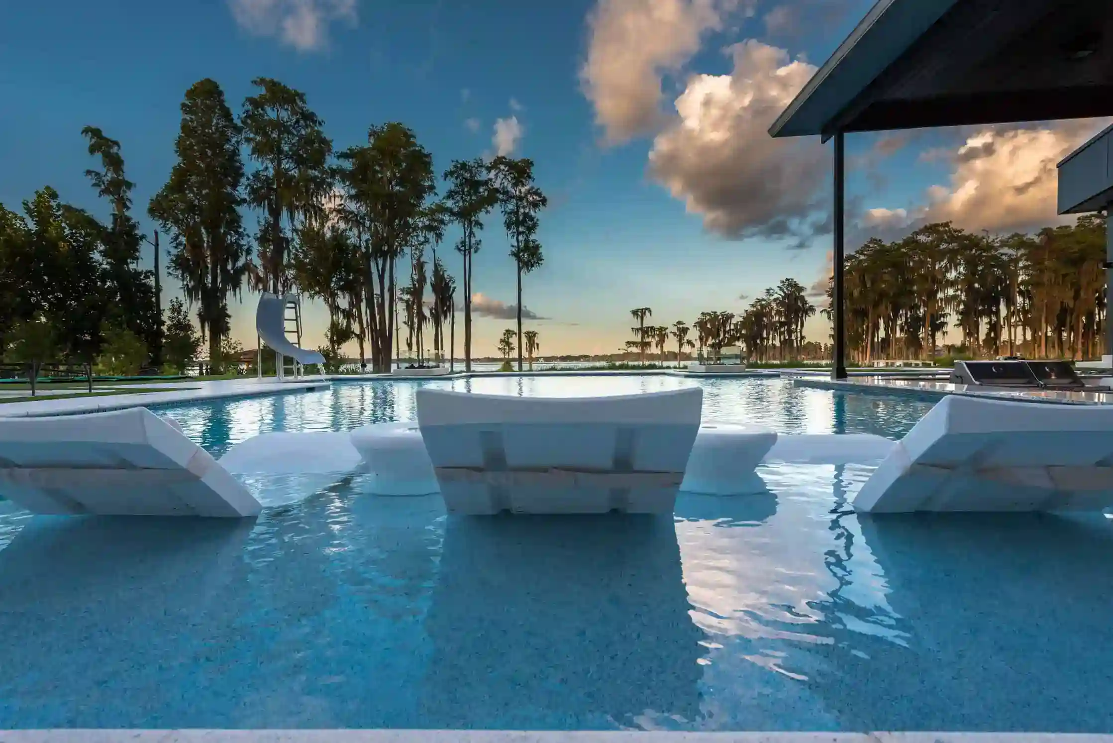 Contemporary backyard pool with white lounge chairs and a waterslide in Timacuan, Lake Mary FL