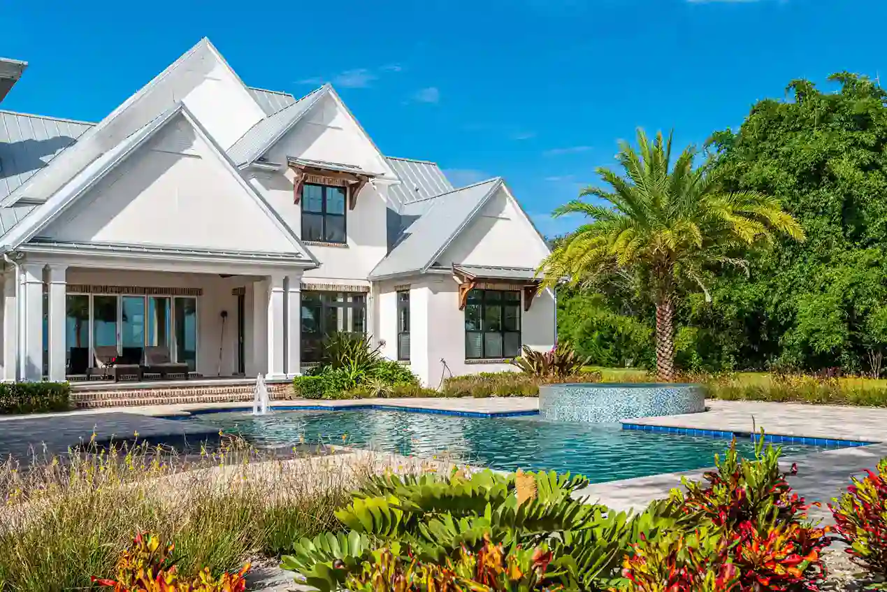 Luxury modern white house with custom-designed pool and lush landscaping in sunny outdoor setting in St. Johns County