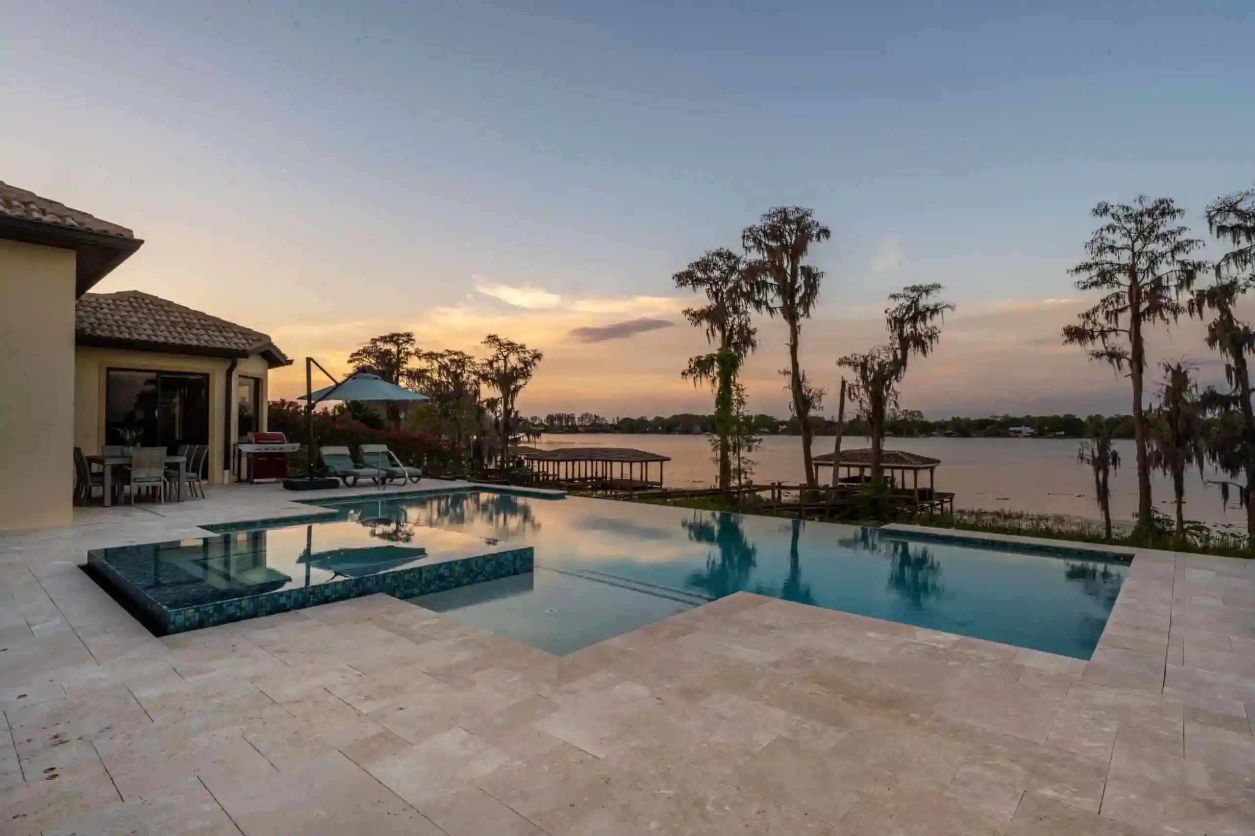 Elegant backyard pool with water views at sunset and modern lounge area in Bay Hill, Dr. Phillips FL
