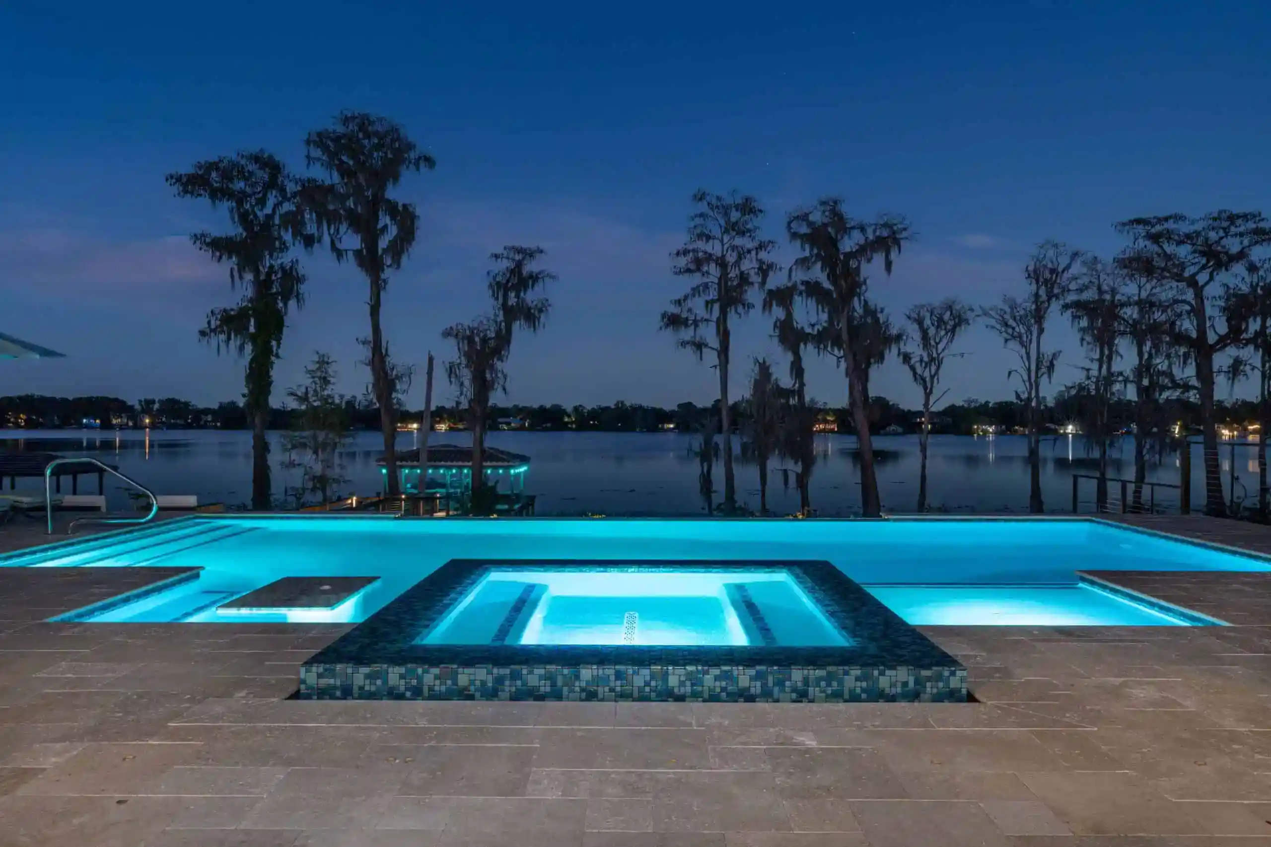 Contemporary illuminated pool with hot tub and water views at night in Sand Lake Hills, Dr. Phillips FL