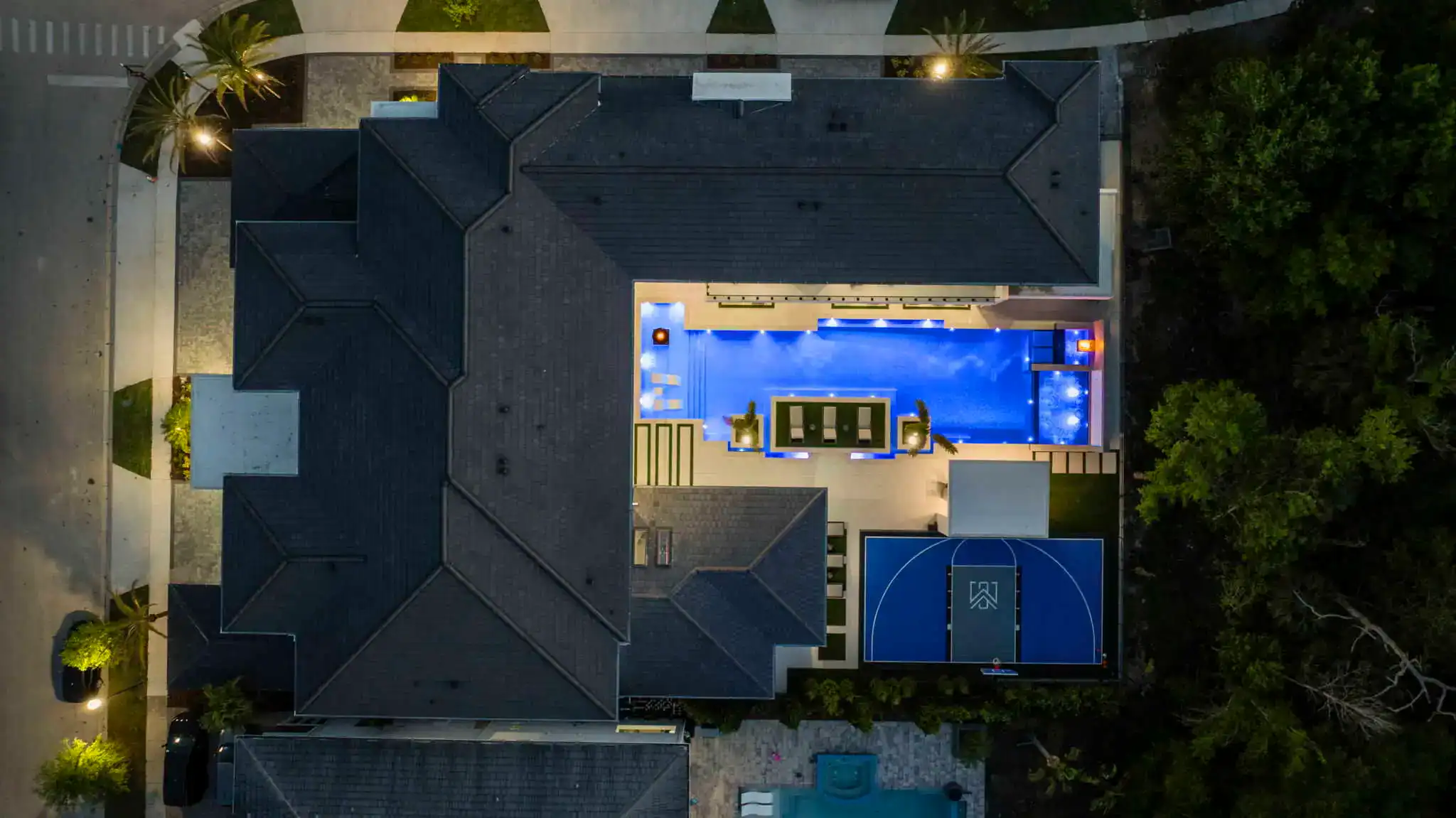 Illuminated backyard pool with modern outdoor furniture at night in Longwood, Seminole County FL