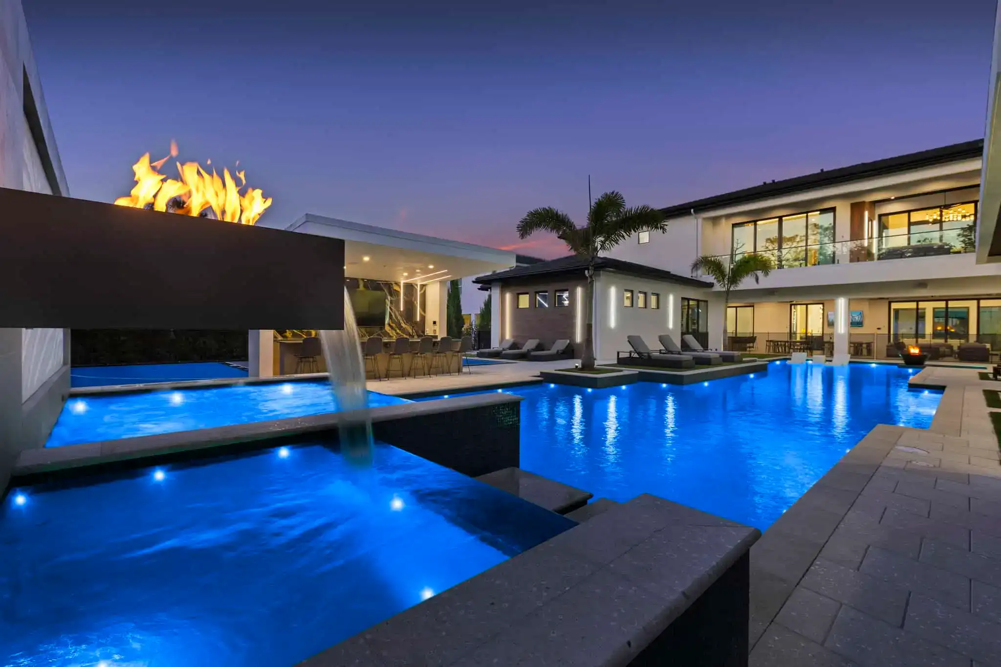 Luxury modern backyard pool with waterfall, fire feature, and contemporary outdoor living space in Indian River Estates, Titusvilee