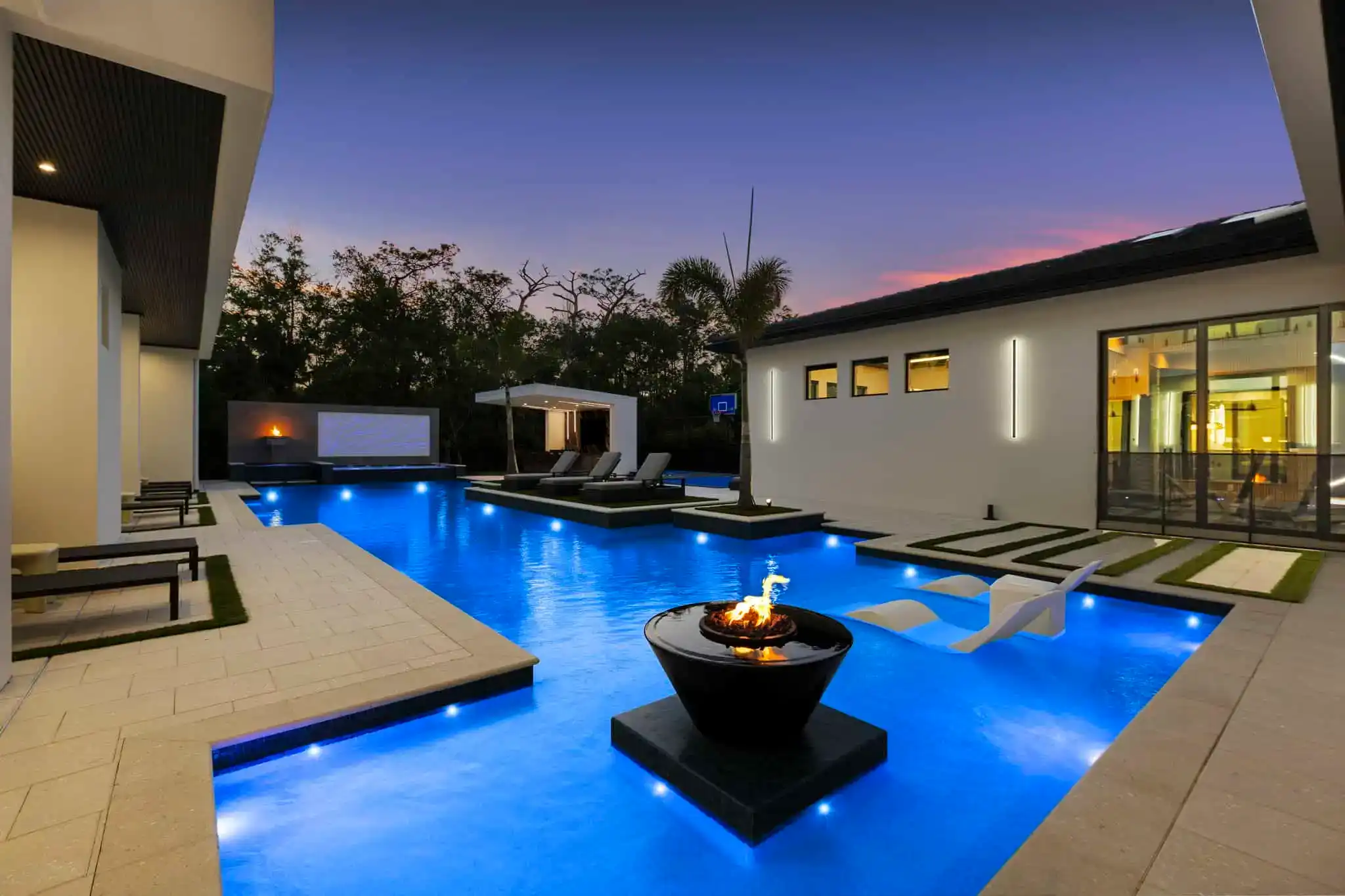 Modern backyard pool with LED lighting and fire feature at dusk in Beachside Homes, Daytona Beach