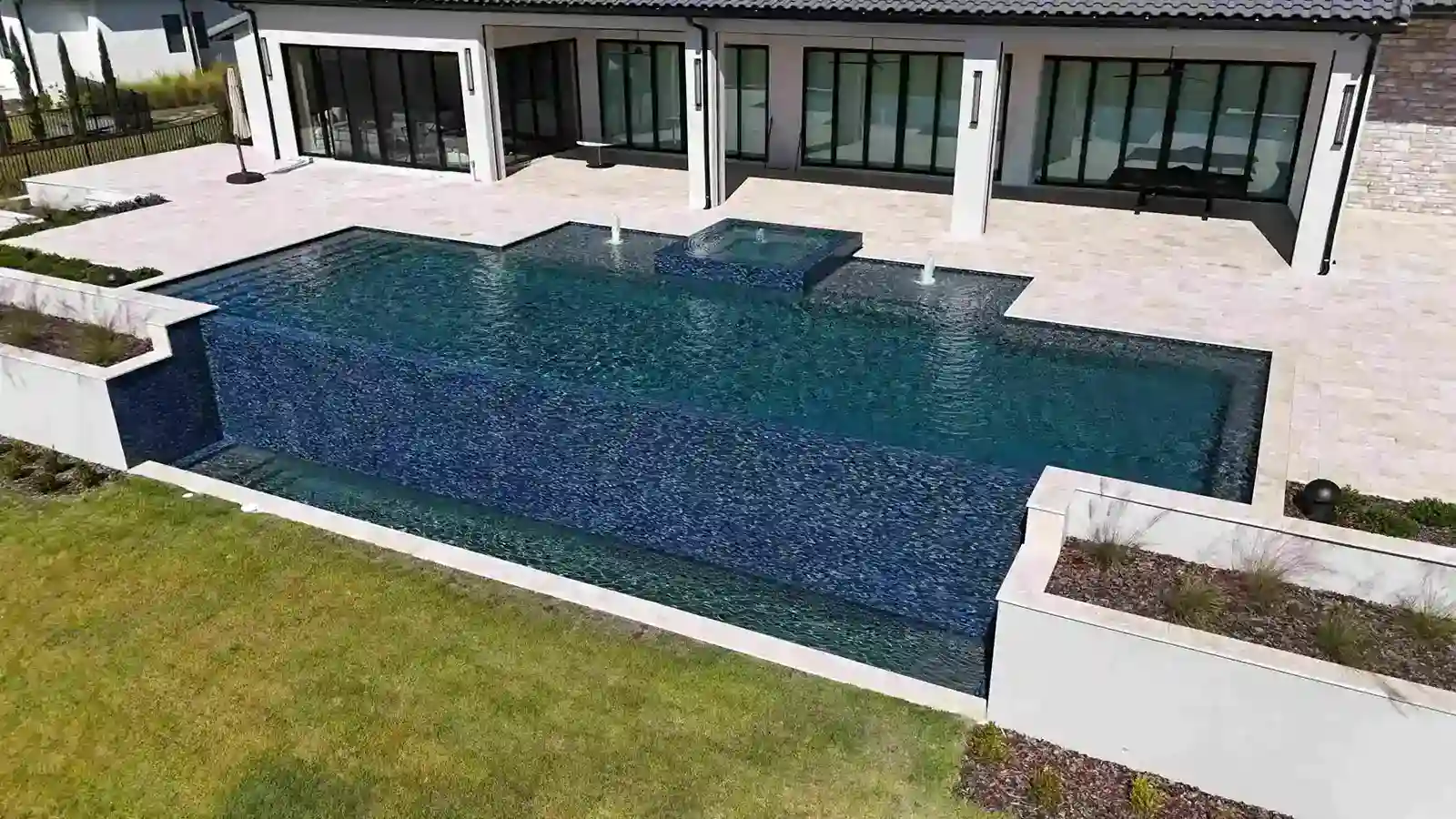 Luxurious modern pool with sleek design and water features beside a contemporary patio