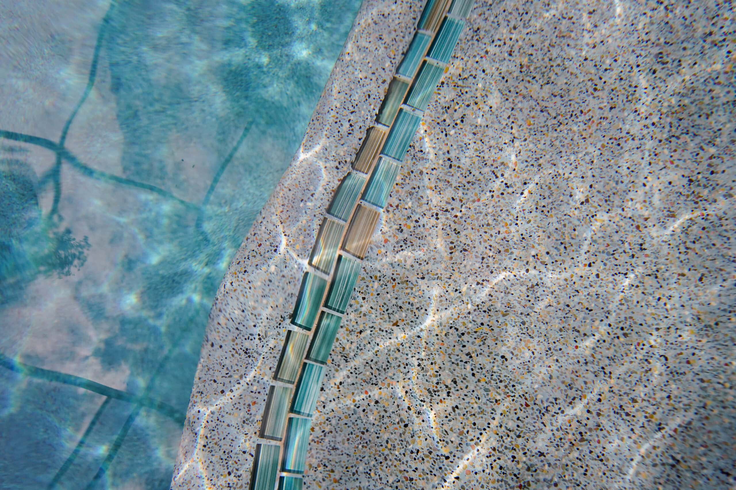 gonzalez-pool-quality-materials Aerial view of a custom-designed luxurious pool with lounge chairs, palm trees, and a spa area.