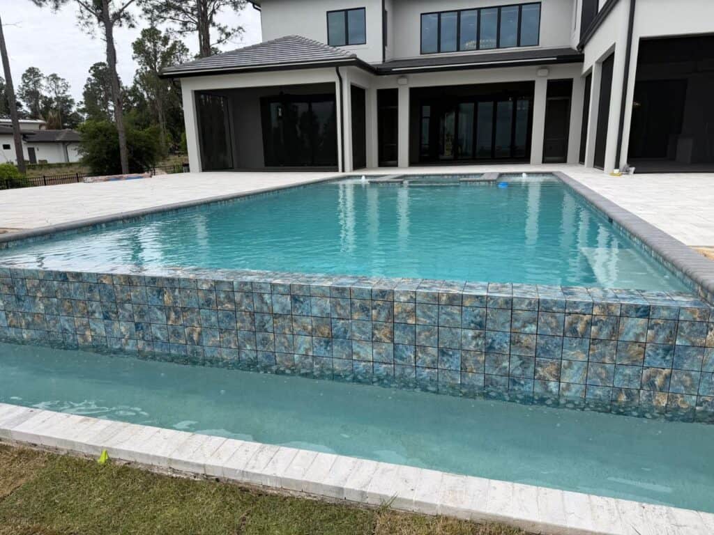 Luxury pool with raised spa and glass mosaic tile wall at a Bella Collina home in Montverde, Florida