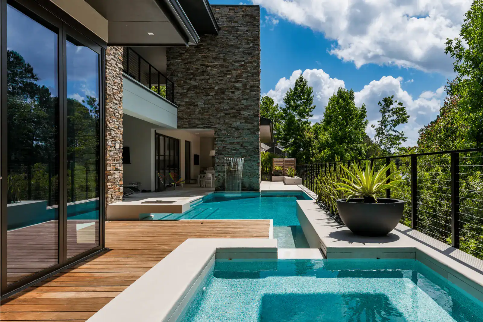 galleryImage-1 Narrow pool and spa with a wood deck running along the glass wall of a modern home